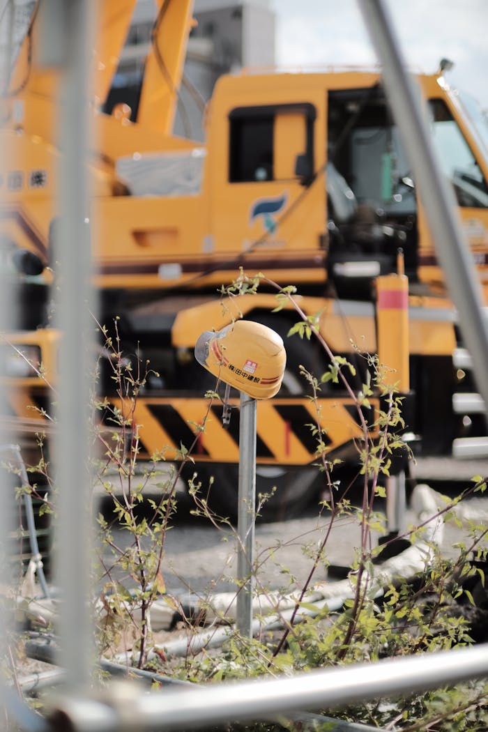 Yellow hard hat on construction site with crane, depicting safety and industry.