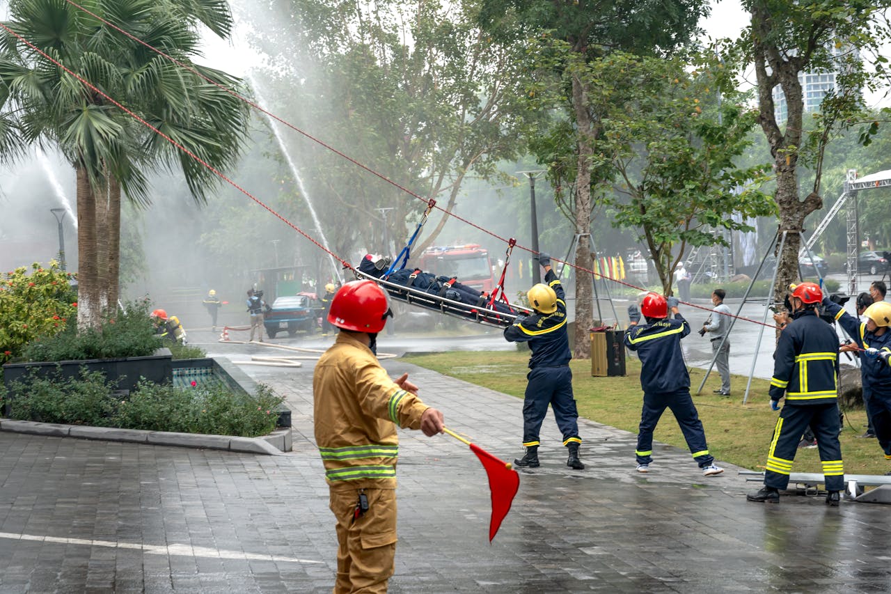 Firefighters performing a high angle rescue operation in an urban setting, demonstrating teamwork and emergency skills.