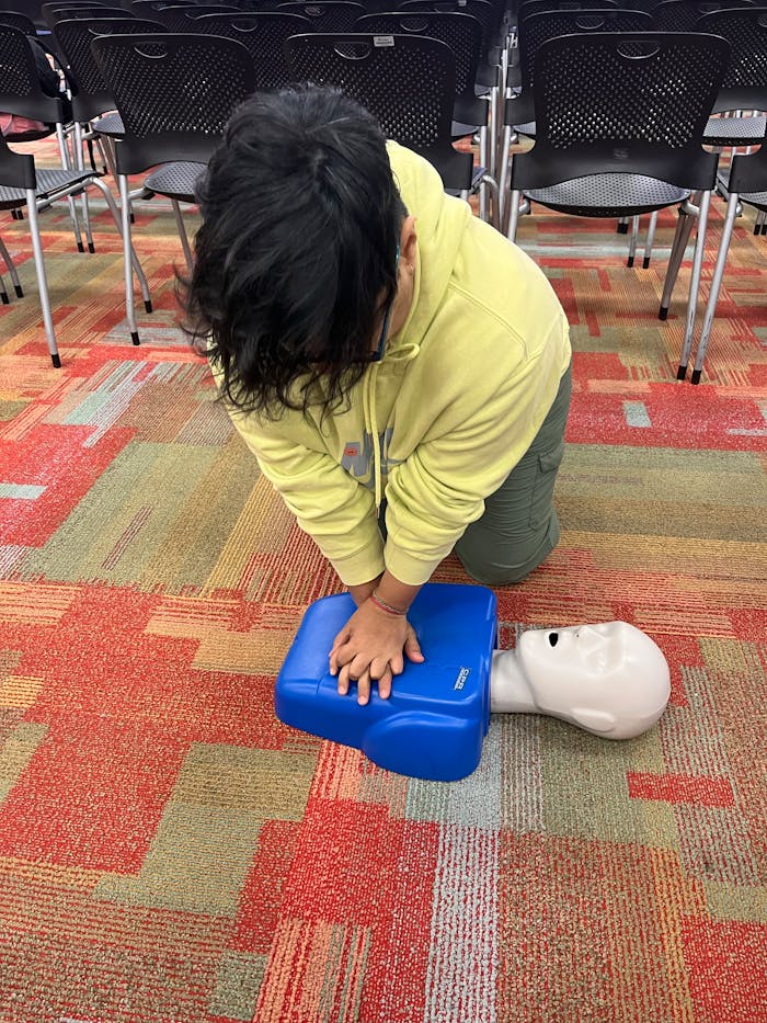 Individual practicing CPR on a training manikin in a classroom setting.